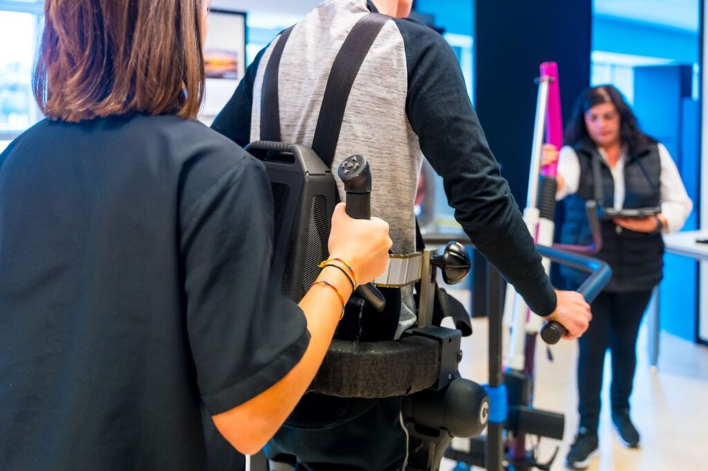 staff assisting patient using exoskeleton for rehabilitation